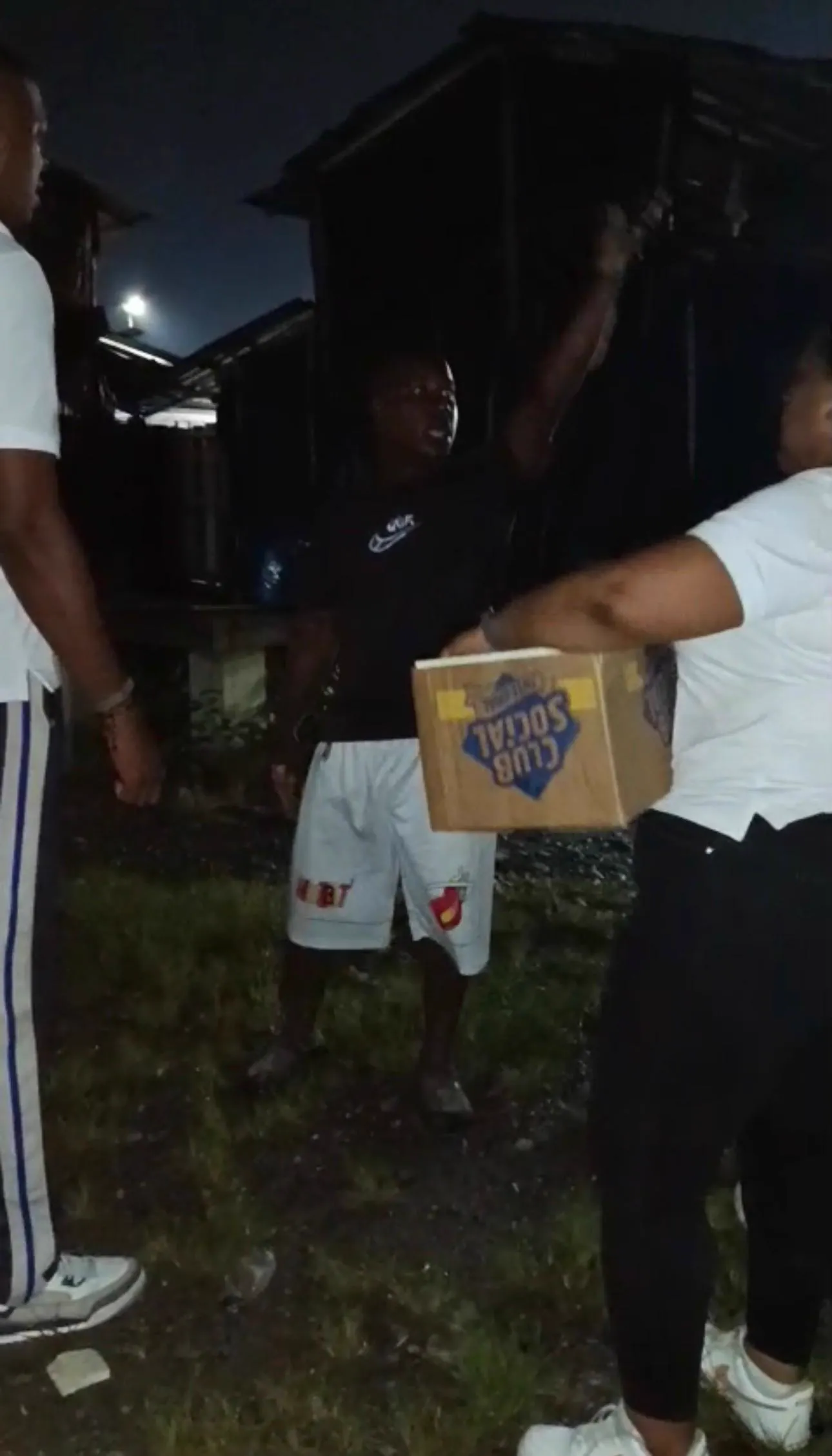 Voluntarios entregan de noche una caja con alimentos a los habitantes de una vivienda