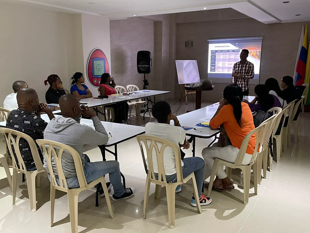Participantes de un taller de formación de la Corporación Luz de Gracia reunidos alrededor de mesas en un salón